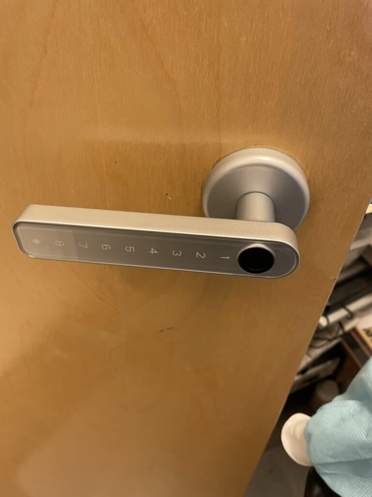 Smart door lock with a numeric keypad and fingerprint reader on a residential door on Summerfield Road in West Falls Church, VA.
